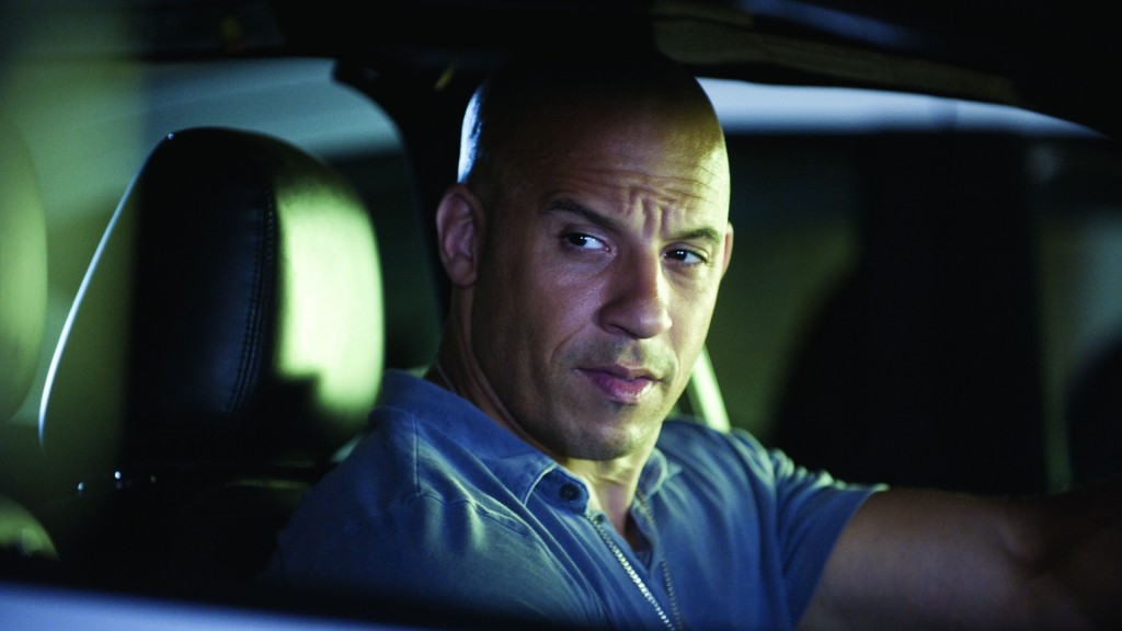 Vin Diesel driving lit by light from outside the car